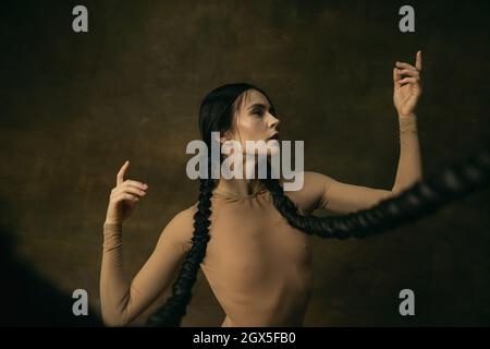 Cropped portrait of spectacular beautiful ballerina with smooth tender movements isolated over vintage green background Stock Photo