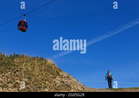 CHAMROUSSE, FRANCE, September 13, 2021 : The hiker on a hard slope and the cable-car cabin Stock Photo