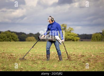 Treasure hunter using a metal detector in a field.  Hertfordshire, UK. Stock Photo