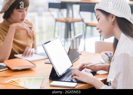 Shot of two young woman working together on digital tablet. Creative female executives meeting in a office using tablet pc and smiling. Stock Photo