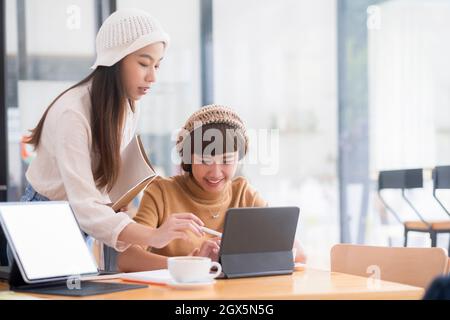 Shot of two young woman working together on digital tablet. Creative female executives meeting in a office using tablet pc and smiling. Stock Photo