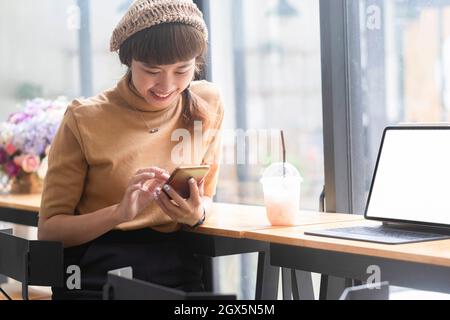 Happy young asian woman using mobile phone Stock Photo