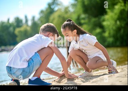 Two kids making sand castles and looking involved Stock Photo