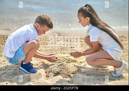 Two kids making sand castles and looking involved Stock Photo