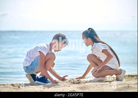 Two kids making sand castles and looking involved Stock Photo