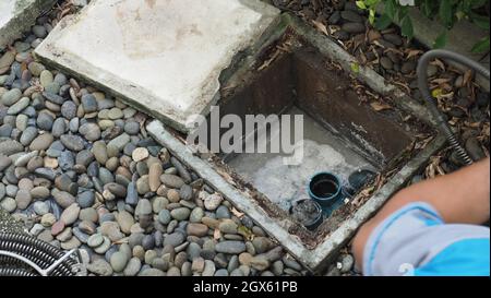 Drain cleaning. Plumber repairing clogged grease trap with auger machine. Maintenance the sewage system and grease trap by professional plumber. Using Stock Photo