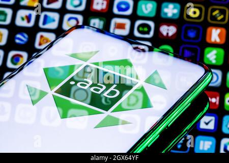 A smartphone with the AAB(Android App Bundle) logo. Many apps icons on the background. Stock Photo