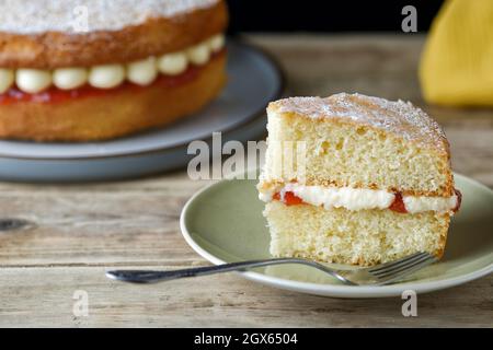 A serving, or slice, of a freshly home made Victoria Sponge and sandwich cake, The cake has a strawberry jam and butter cream filling Stock Photo