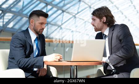 Two business men in modern office building cafe working with laptop Stock Photo