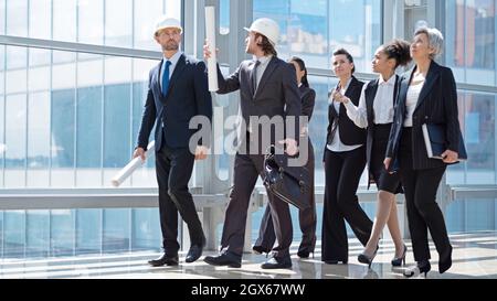 Team of construction industry workers engineer architect business people professionals walking together in modern lobby Stock Photo