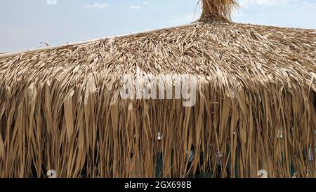 fragment of straw umbrella. thatched umbrella on a beach. Stock Photo