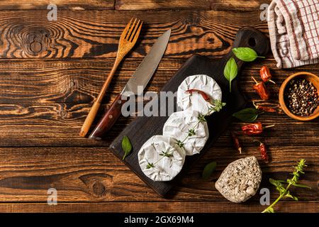 Camembert cheese on a rustic background. Noble cheese with mold. An overhead view of cheese with noble white mold and walnuts on a cutting board Stock Photo