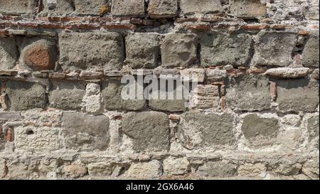 stone wall. small bricks are placed between large stones. fragment of an ancient castle Stock Photo