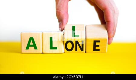 All or alone and support symbol. Businessman turns the wooden cube and changes the word alone to all. Beautiful white background. Business and all or Stock Photo