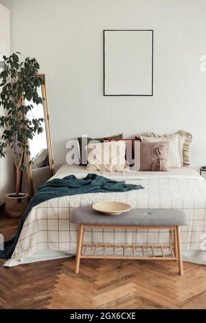 Light bedroom rustic interior with natural materials. Wooden furniture and cotton textiles. Mock up frame on wall Stock Photo