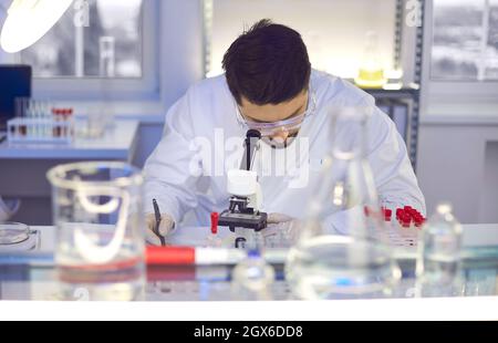 Young man in the laboratory looks through a microscope. Stock Photo