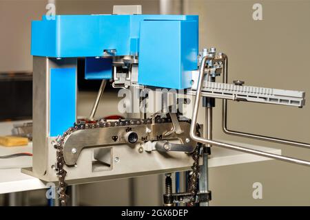 Professional industrial machine with a blue casing for sharpening chains of chainsaws close-up on a gray-beige background. Stock Photo