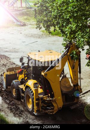 Yellow excavator loader removes the remains of broken asphalt.  Stock Photo