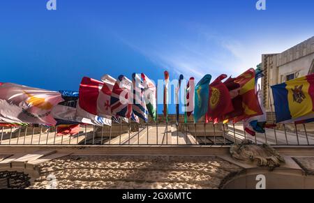 VIENNA, AUSTRIA - MAY 7, 2018: Different flags of many countries on building facade, sky background. Bottom view Stock Photo