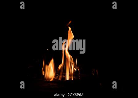 Fire in the fireplace on a dark background. Firewood in flames. An intimate atmosphere by the fire. Stock Photo
