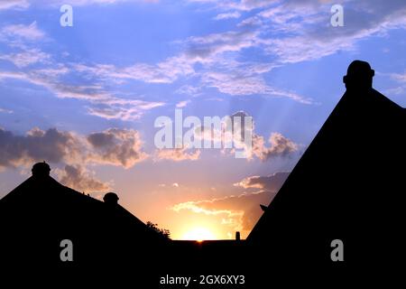 Sunrise in the suburbs. Buildings with orange sunrise and rays with blue sky and clouds. Stock Photo