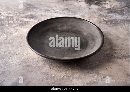 Empty dark deep plate on gray textured background as concrete. Close up, copy space Stock Photo