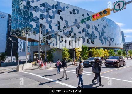Calgary, Alberta, Canada - 27 September 2021:  People crossing the street in front of Calgary Public Library Stock Photo