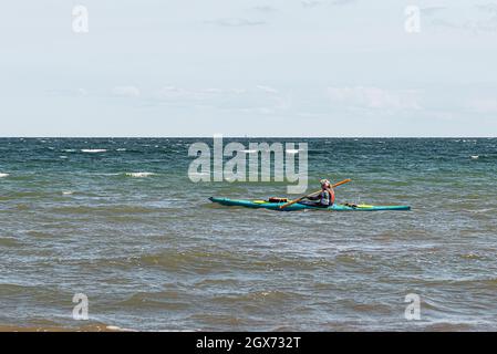 girl wearing life vest paddles alone in a kayak on the open sea, Vejle, Denmark, August 31, 2021 Stock Photo