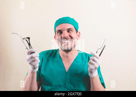 Young smiling doctor with medical instruments in his hand in green surgeon suit isolated Stock Photo