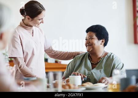 Portrait of smiling young woman caring for senior African-American patient in nursing home, copy space Stock Photo