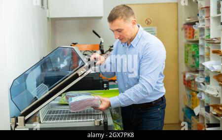 Worker using vacuum packing machine in printing shop Stock Photo