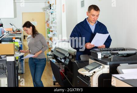 Printing company employees work on various printing machines Stock Photo