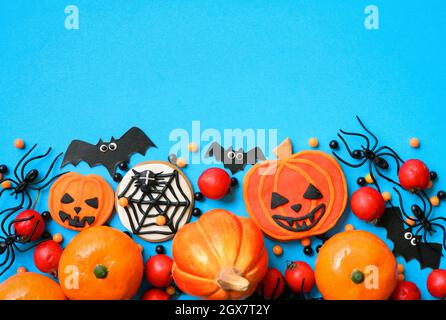 Halloween background with cookies, spiders and bats, top view. Halloween funny objects on blue table with space for greeting text. Hallowen food and d Stock Photo