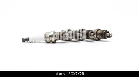Close up four used spark plugs isolated on white background. Stock Photo