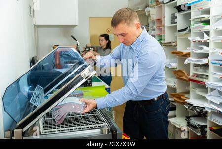 Worker packs notebooks in a vacuum packing Stock Photo