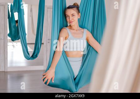 Young beautiful woman practicing aerial yoga in gym.  Stock Photo