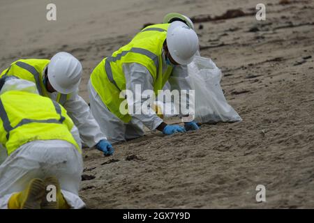 Huntington Beach, California, USA. 4th Oct, 2021. Workers in protective suits clean up an area of the beach after a major oil spill dumped 126,000-gallon oil from an offshore oil platform. A massive oil spill off the Orange County coast in Southern California prompted the closure of a 9-kilometer long beachfront area and crews from the California Department of Fish and Wildlife (CDFW) are cleaning up the pollution from facilities in federal waters. (Credit Image: © Jason Ryan/ZUMA Press Wire Service) Stock Photo