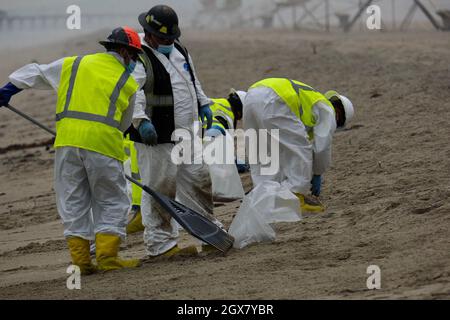 Huntington Beach, California, USA. 4th Oct, 2021. Workers in protective suits clean up an area of the beach after a major oil spill dumped 126,000-gallon oil from an offshore oil platform. A massive oil spill off the Orange County coast in Southern California prompted the closure of a 9-kilometer long beachfront area and crews from the California Department of Fish and Wildlife (CDFW) are cleaning up the pollution from facilities in federal waters. (Credit Image: © Jason Ryan/ZUMA Press Wire Service) Stock Photo