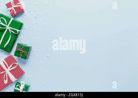 Christmas and New Year blue flat lay with various red, white and green present gift boxes top view. Gift ribbon and striped tabby packaging paper. Cop Stock Photo
