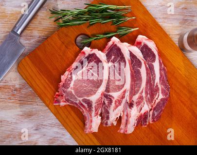 Raw pork's chops and rosemary on wooden surface Stock Photo