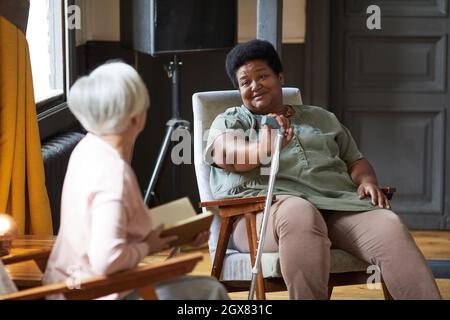 Portrait of senior African-American woman talking to friends while enjoying retirement in nursing home Stock Photo