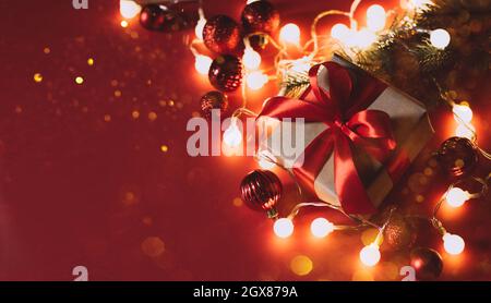 Festive Christmas boxes with a satin red bow red background with Christmas balls, garland sparkles with confetti lights Stock Photo