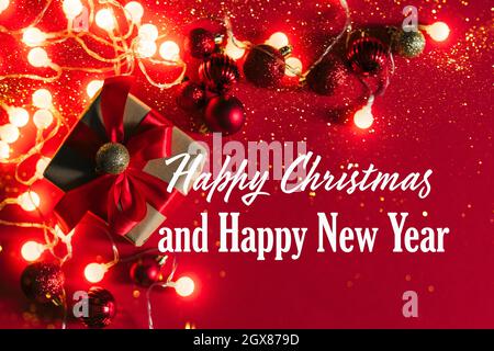 Festive Christmas boxes with a satin red bow red background with Christmas balls, garland sparkles with confetti lights Stock Photo