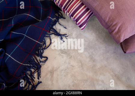 Pillow blanket. Blue plaid woolen thin plaid with striped purple pillow on a gray background with copy space. The concept of home comfort, warm winter Stock Photo