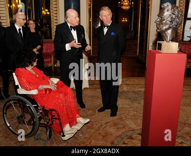 Prince Charles, Prince of Wales and actress Dame Elizabeth Taylor, sitting in a wheelchair, look at a bust of Welsh actor Richard Burton during a Royal Welsh College gala evening at Buckingham Palace in London, on April 29, 2010. Stock Photo