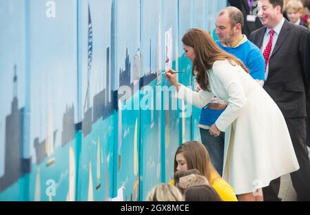 Catherine, Duchess of Cambridge, wearing a Max Mara Villar belted wool coat, paints a yacht on a mural as she visits the new home of Ben Ainslie Racing and the1851 Trust in Portsmouth on February 12, 2015. Stock Photo