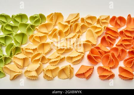Rows of colorful raw pasta shaped as corners on isolated background, italian food concept Stock Photo