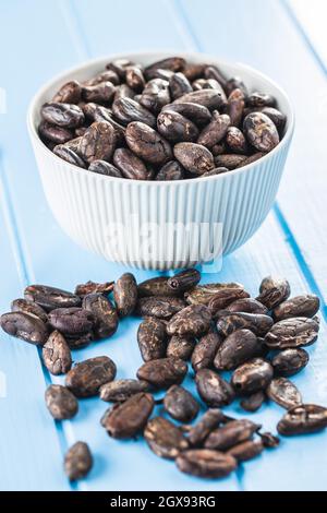 Roasted cocoa beans on blue table Stock Photo