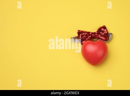 red rubber heart on a yellow background, top view Stock Photo