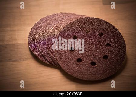 Close up shot of some sandpaper round pieces on a wooden table. Stock Photo